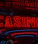 Neon lights display the word 'CASINO' in bright red, standing out against a dark background. The vibrant glow reflects a lively and bustling atmosphere.