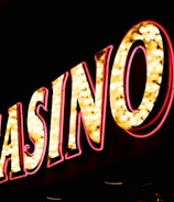 Brightly illuminated letters spell out 'CASINO' with glowing yellow bulbs and red outlines against a dark background.